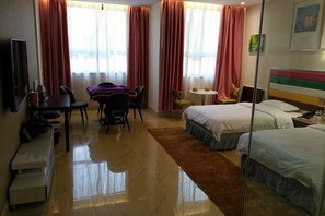 A hotel room with a bed, a desk, a chair, a small table, and a TV.