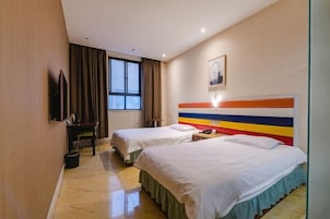 A hotel room with two beds, a desk, a chair, a television, and a window with curtains.