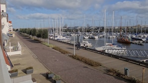 Un port de plaisance où de nombreux bateaux sont amarrés le long d’une promenade dallée.