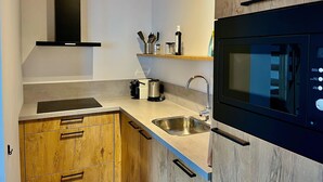 Een moderne keuken met houten kastjes, een RVS spoelbak, een magnetron en een ingebouwde oven.