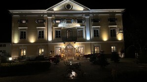 Een groot, goed verlicht gebouw met een centrale ingang, meerdere ramen en een symmetrische gevel.