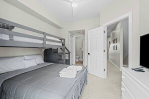 Une chambre avec des lits superposés, une télévision et une porte donnant sur une salle de bain.