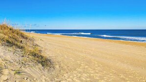 Ein Sandstrand mit Wellen und blauem, klarem Himmel.