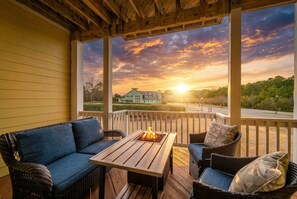 A covered outdoor seating area with a fire feature, overlooking a residential area during sunset. - Aviation Themed Townhome w/ Waterpark & Game Room - Pet Friendly (Kill Devil Hills)