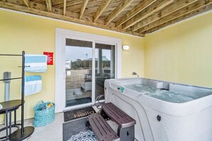 Un espace détente avec un jacuzzi, un banc, un porte-serviettes et une porte donnant sur l’extérieur.
