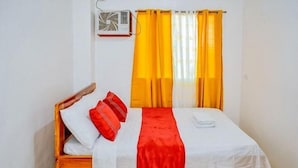 A single bed with a wooden frame, white bedding, red pillows, and a red throw. - RedDoorz Plus @ Papa Tasie Camotes (San Francisco)
