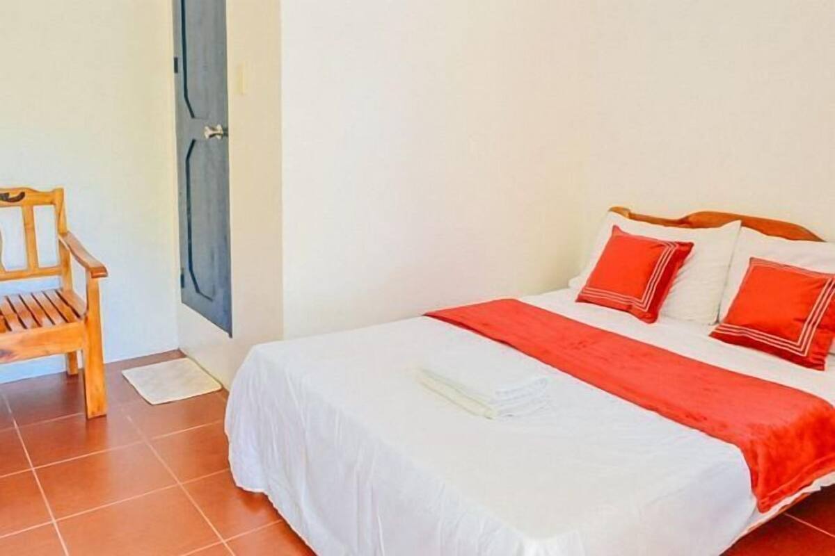 Un dormitorio con una cama, una silla de madera y una puerta.
