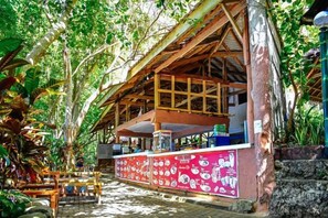 A rustic wooden structure with a covered seating area and a counter with a colorful menu. - RedDoorz Plus @ Papa Tasie Camotes (San Francisco)