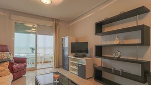 Una sala de estar moderna con sofá, mesa de centro, televisor y estanterías.