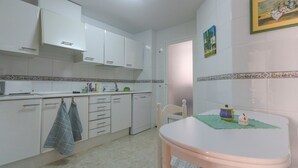 Una cocina con armarios blancos, lavavajillas y una mesa con mantel individual verde.