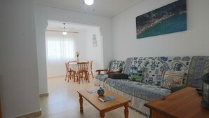 Ein Wohnzimmer mit einer Couch, einem Couchtisch und einem Essbereich mit Stühlen und einem Tisch.
