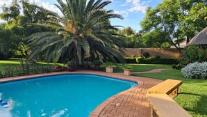 Une piscine avec une terrasse en briques et un palmier.