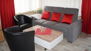 A living room with a grey sofa, red cushions, a black armchair, and a wooden coffee table. - Lovely Apartment in Kirn (Kirn)