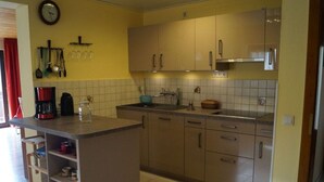 A compact kitchen with a central island, light-colored cabinets, and a tiled backsplash. - Lovely Apartment in Kirn (Kirn)