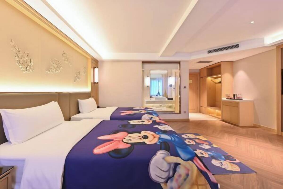 A hotel room with two beds, a large mirror, and a desk with a lamp.