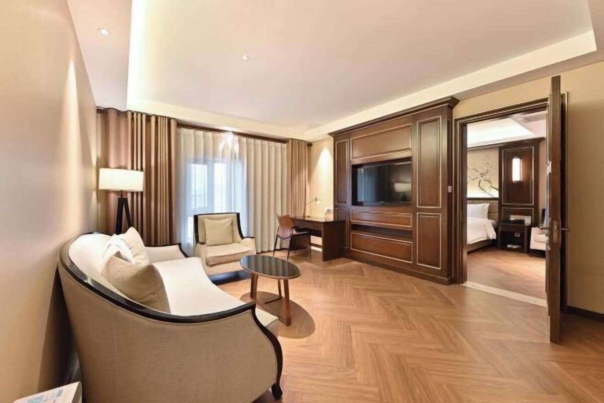 A hotel room with a sofa, a TV, a desk, and a wardrobe.