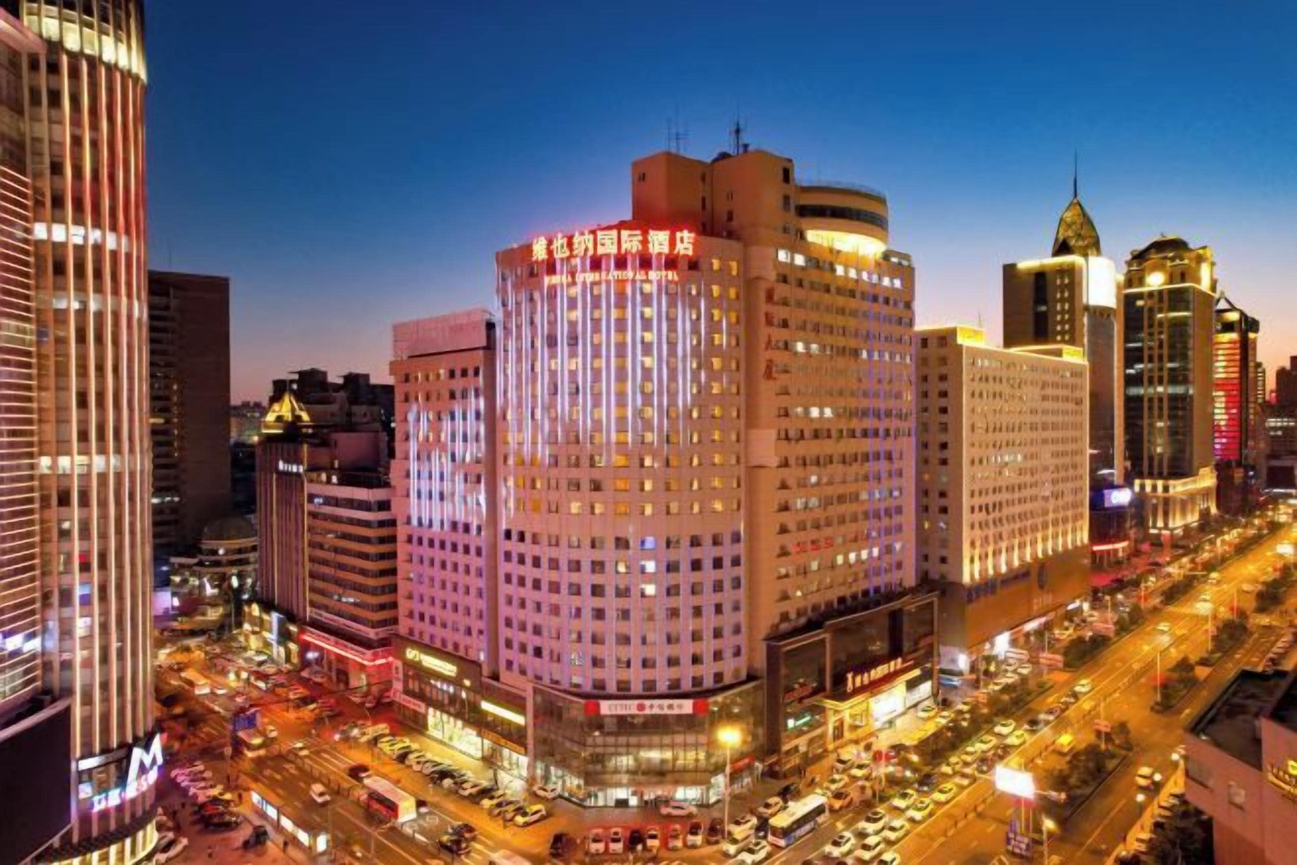 A cityscape with a prominent hotel featuring a corner location, multiple floors, and a well-lit facade.