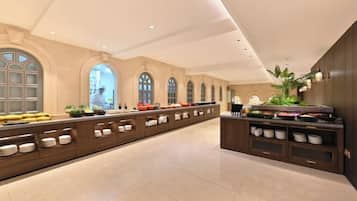 A spacious hotel lobby with a long reception counter, arched windows, and a modern ceiling design.