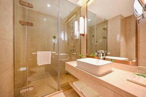 A modern bathroom with a glass-enclosed shower, a large mirror, and a white sink.
