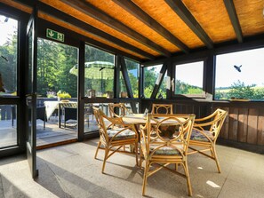 Un patio al aire libre con mobiliario de mimbre y vistas al follaje circundante.