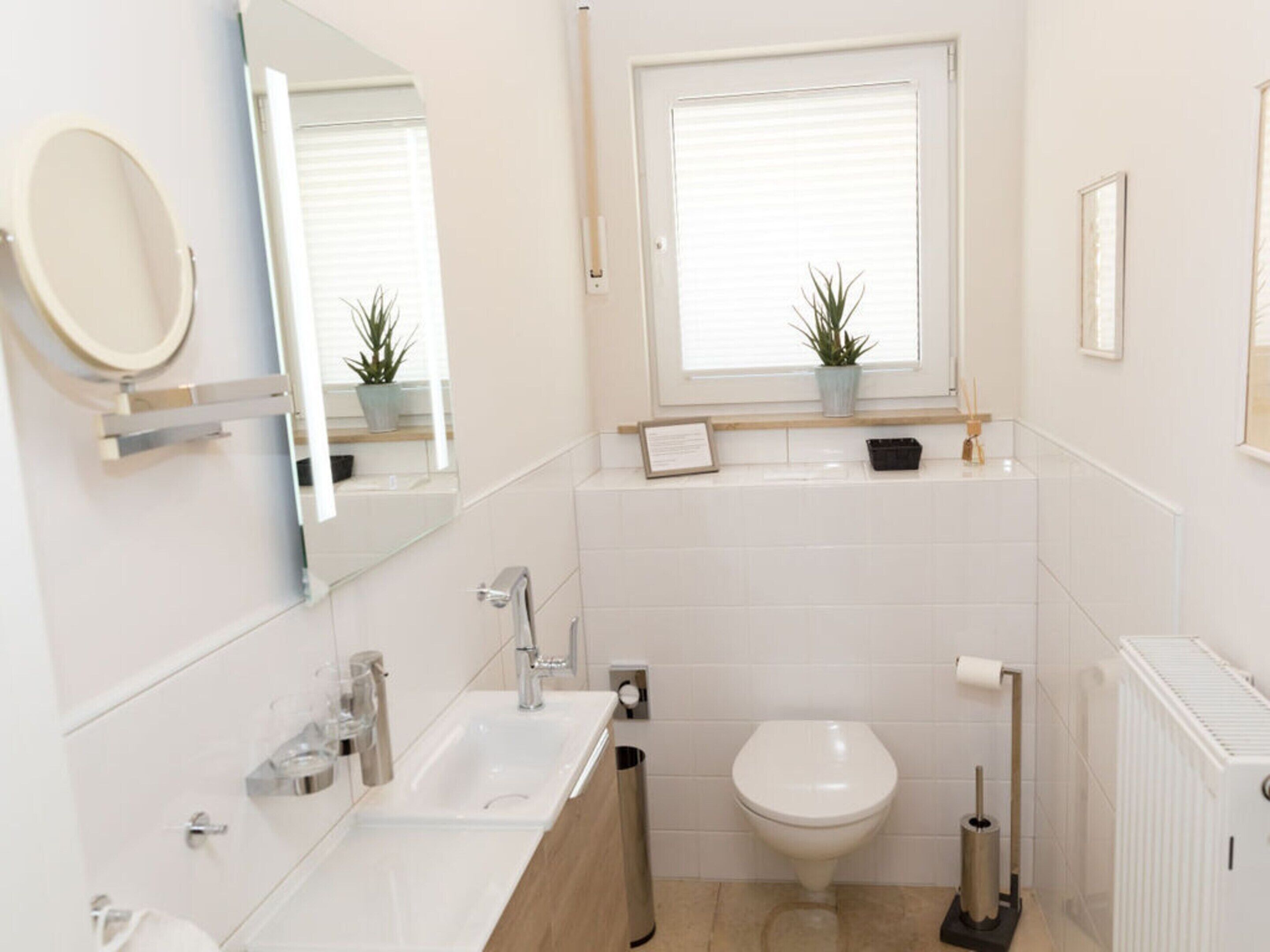 A modern bathroom with a sink, toilet, and window.