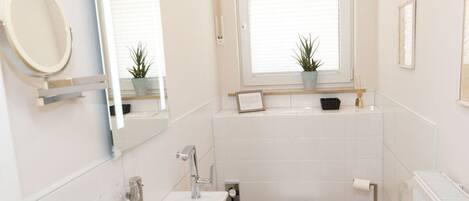 A modern bathroom with a sink, toilet, and window.