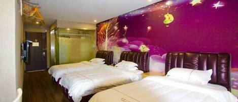 A hotel room with two beds, a purple wall mural, and a wooden floor.