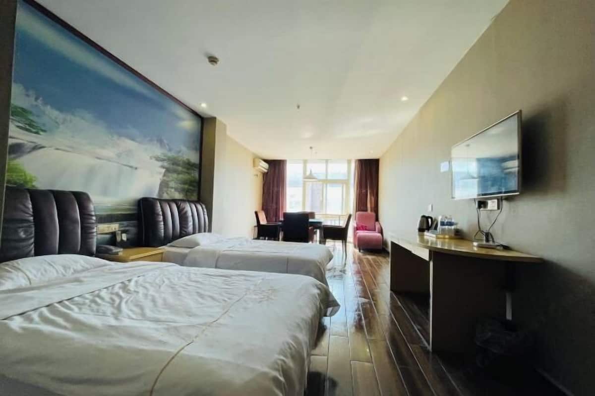 Habitación de hotel con dos camas, un sofá, un televisor y un escritorio.