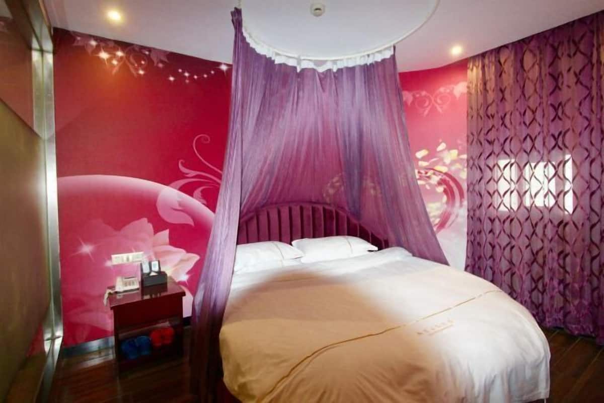 Un dormitorio con cama de dosel, una mesita de noche con lámpara y un muro decorativo.