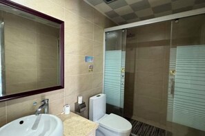 A bathroom with a sink, mirror, toilet, and shower stall. - Dongyuan Business Hotel (Pinghu)
