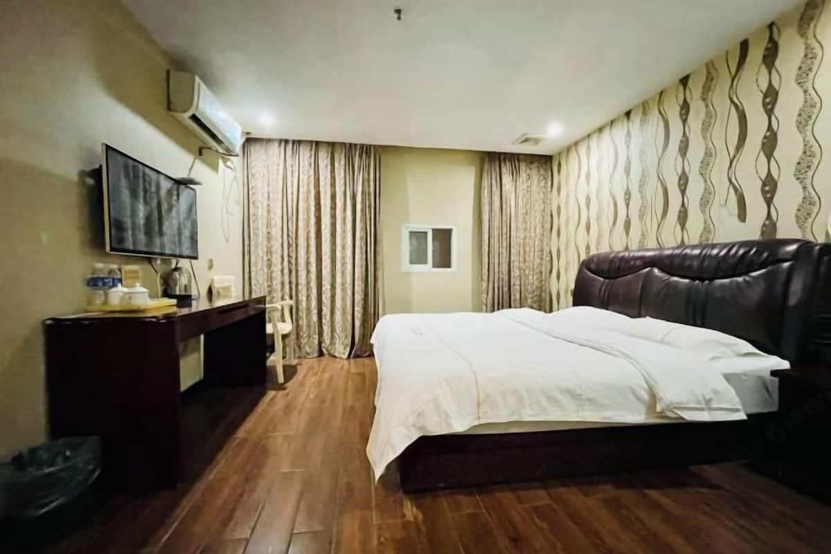 Una habitación de hotel con cama, escritorio, televisor y cortinas.