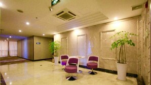 A hotel lobby with marble flooring, purple chairs, and potted plants. - Dongyuan Business Hotel (Pinghu)