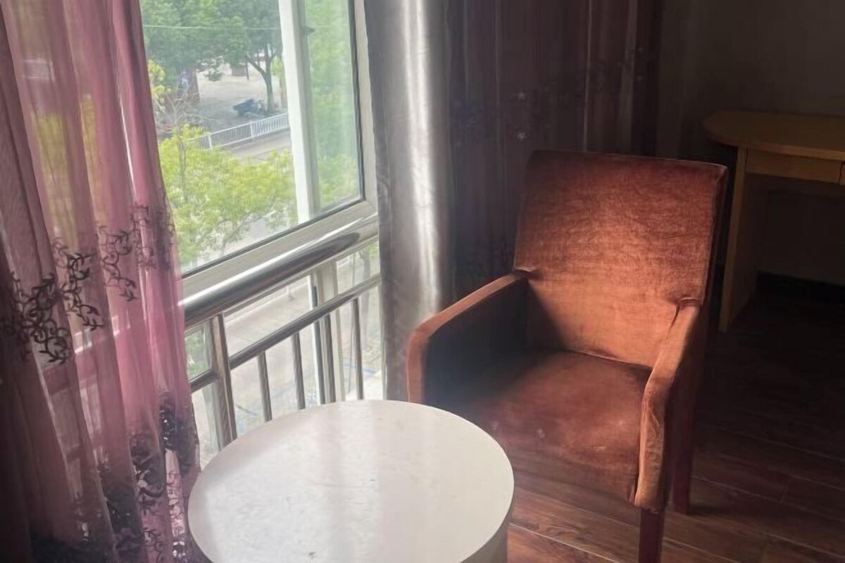 A room with a large window, a chair, and a small table.