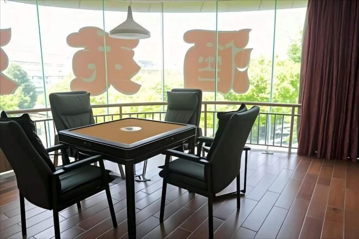 Una habitación con mesa de billar, cuatro sillas, un ventanal con cortinas y vistas a zonas verdes.