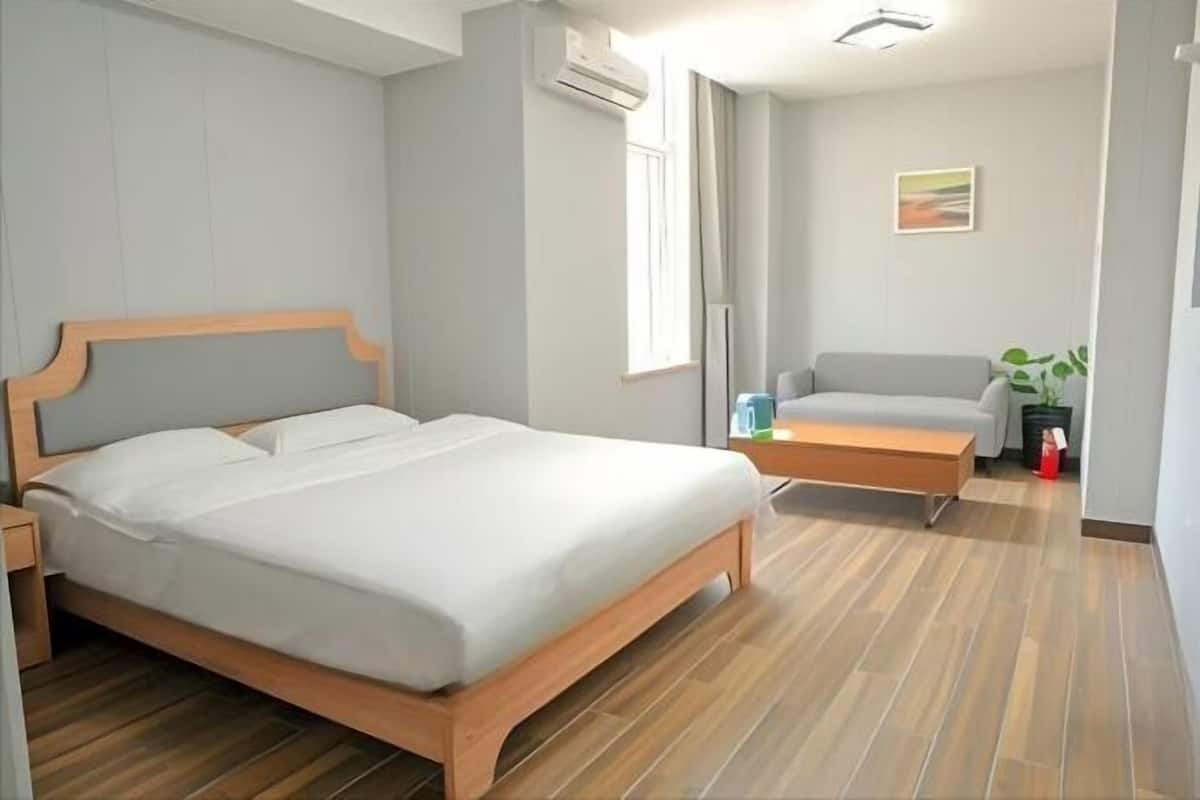 Un dormitorio con cama, mesita de noche, silla, pequeña mesa y una planta.