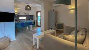 A modern living room with a sofa, a small table, and a kitchen in the background. - Apt. Azure, central, parking, top for 6 (San Pantaleo)