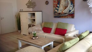 A living room with a sofa set, a coffee table, and a painting on the wall. - Watt's Dream Close to the Beach (Büsum)