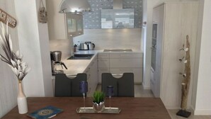 A modern kitchen with white cabinets, a stainless steel sink, and a hanging light fixture. - Watt's Dream Close to the Beach (Büsum)