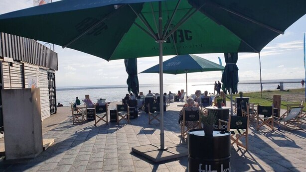 An outdoor seating area with umbrellas and chairs, overlooking a body of water. - Watt's Dream Close to the Beach (Büsum)