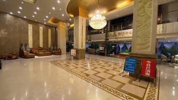 A spacious lobby with a checkered floor, a chandelier, and a seating area with sofas.