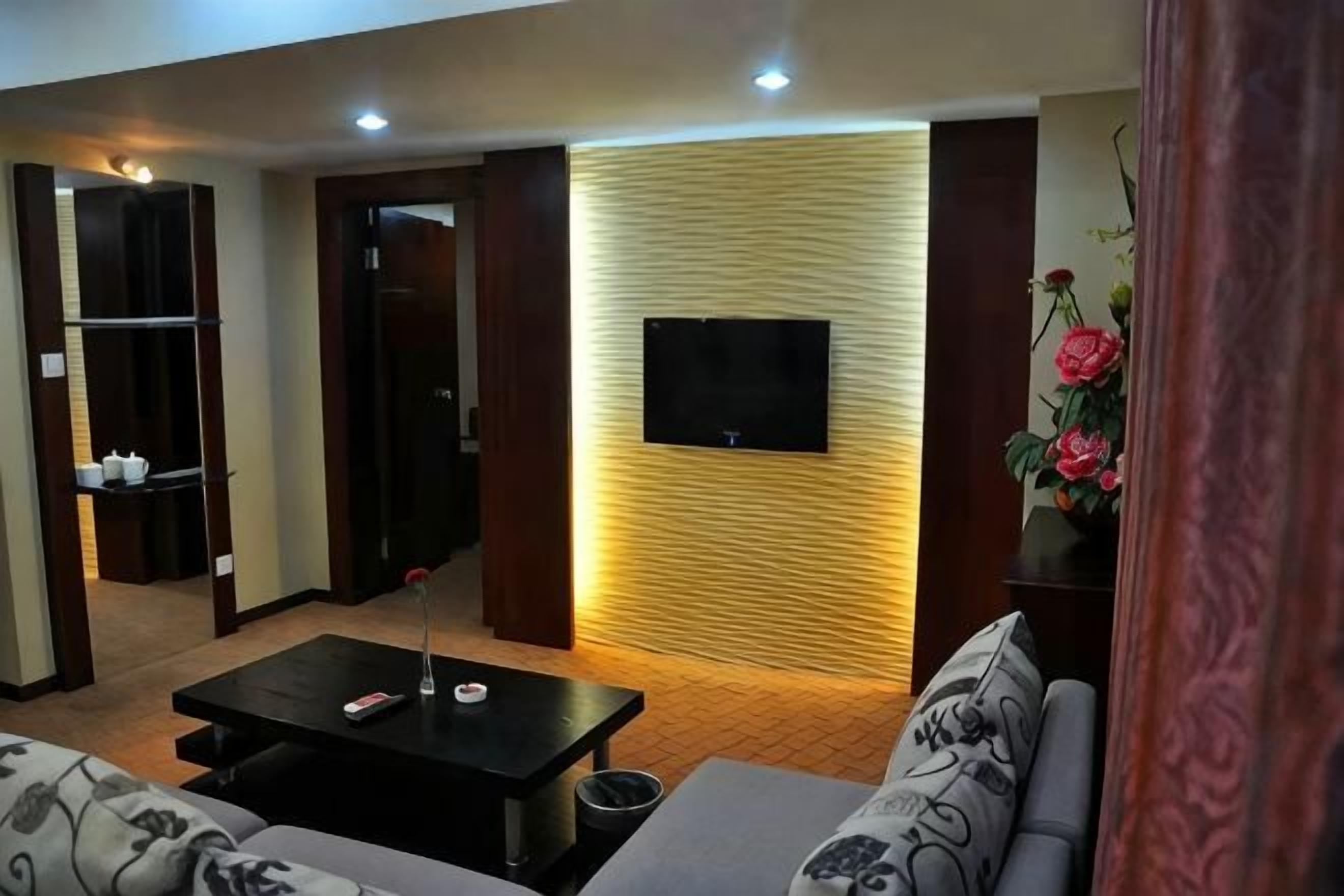 A living room with a sofa, a coffee table, a TV mounted on a wall, and a wooden panel design.