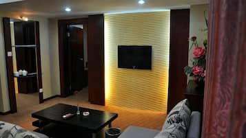 A living room with a sofa, a coffee table, a TV mounted on a wall, and a wooden panel design.