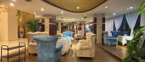 A hotel lobby with seating areas, a reception desk, and a plant.