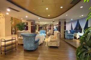 Un vestíbulo de hotel con zonas de estar, una recepción y una planta.