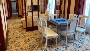 Une pièce avec une moquette à motifs, une table entourée de chaises et des paravents décoratifs.