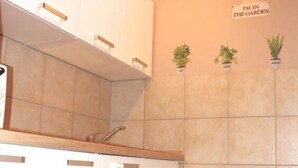 Une cuisine avec des armoires blanches, un comptoir et un panneau accroché au mur sur lequel on peut lire : « PM DANS LE JARDIN ».