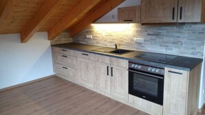Eine Küche mit Steinrückwand, Holzschränken, einer schwarzen Arbeitsplatte und einem eingebauten Backofen.