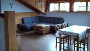 Ein geräumiges Loft mit hohen Decken, einer integrierten Couch, einem Esstisch mit Stühlen und einer kleinen Küchenzeile.
