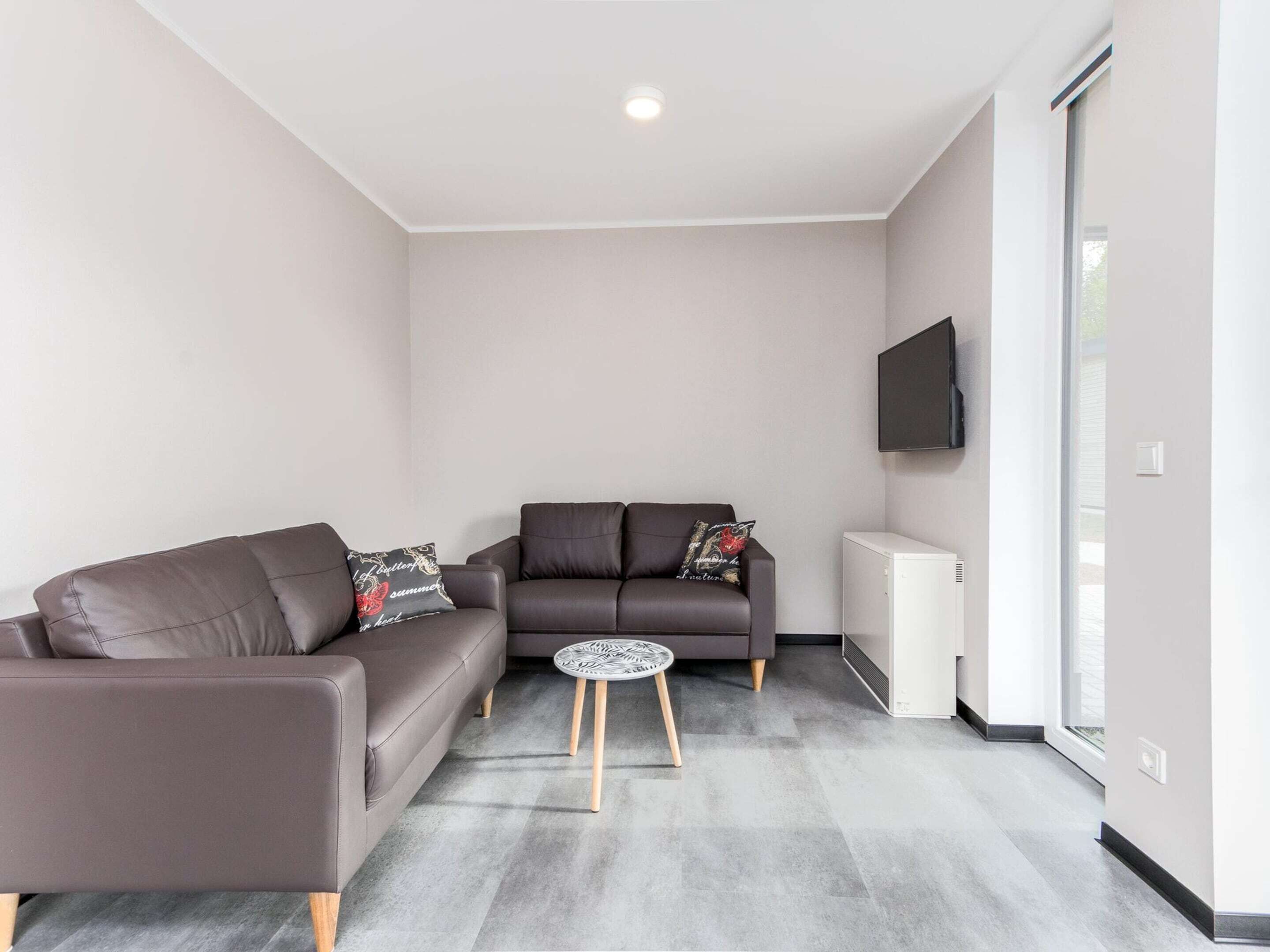 A modern living room with two sofas, a small round table, and a white radiator.