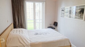 A bedroom with a bed, a window with curtains, a chair, and a framed picture on the wall. - Apartment in Nieuwpoort With Terrace (Nieuwpoort)
